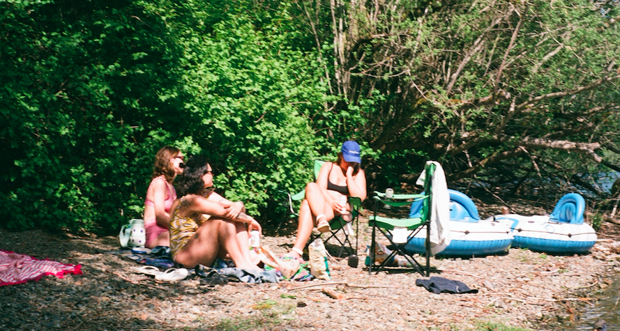 A decorative image of three ladies relaxing on a beach after floating in their inner tubes. 